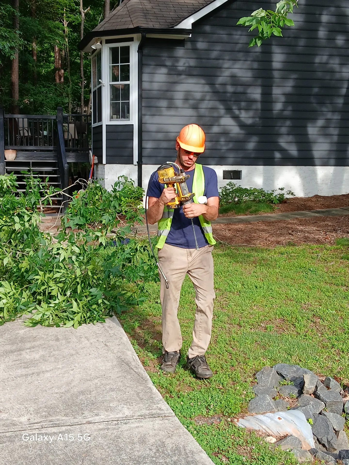 Crew member in hi-vis vest doing ground-side work outside a residence