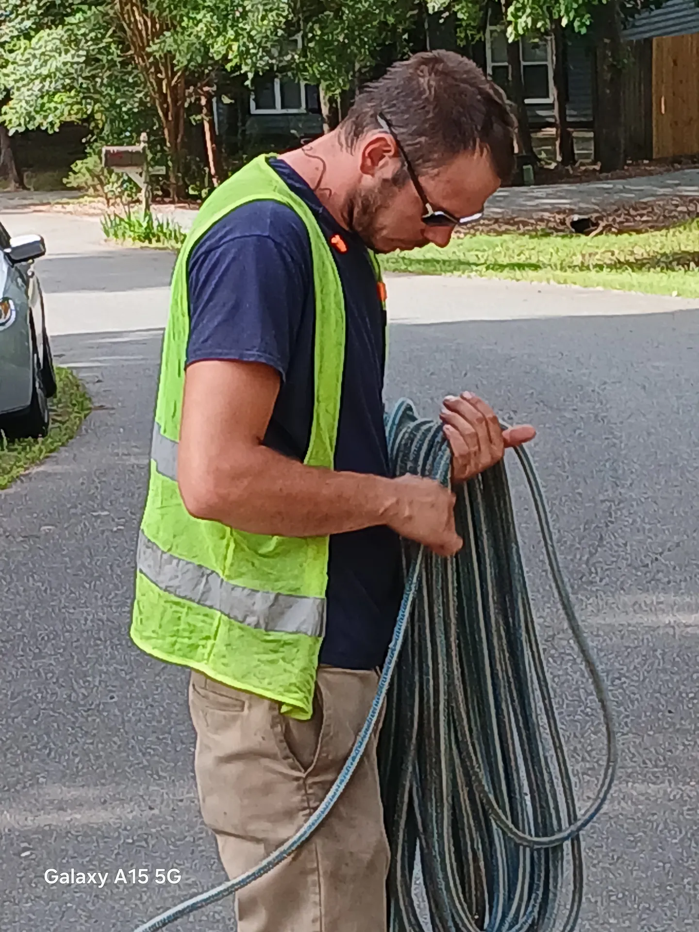 Groundsman coiling a rigging line at the curb after a takedown
